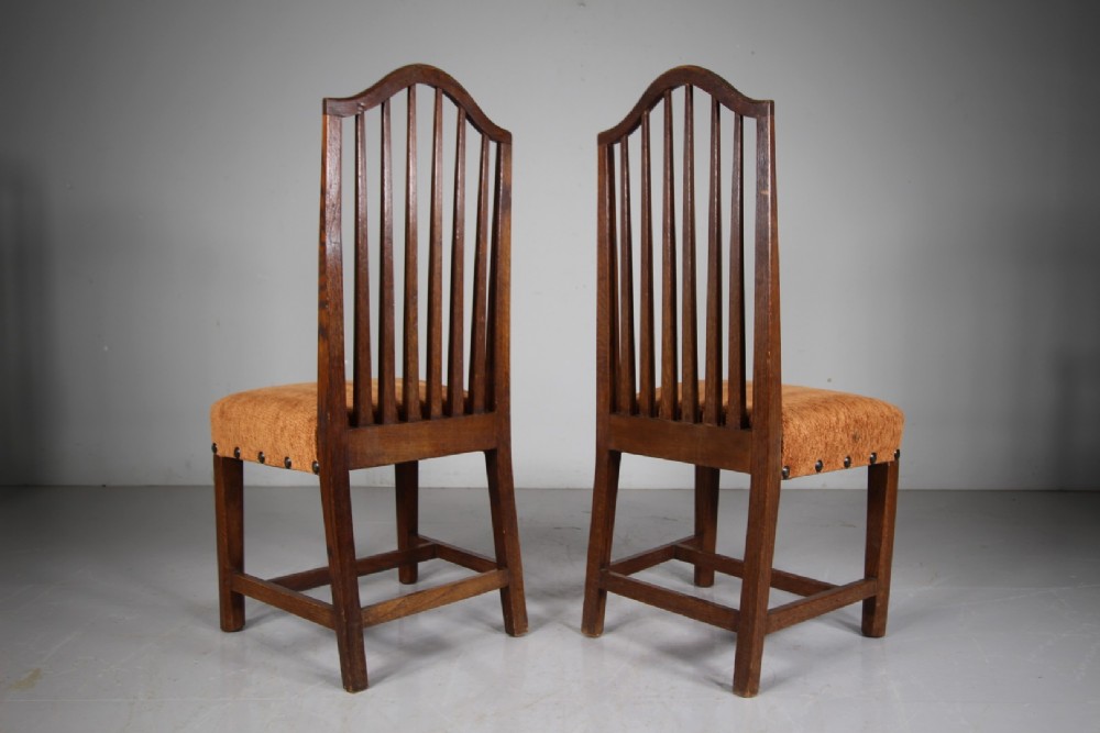 Set of six solid oak Arts and Crafts dining chairs featuring tall spindled backs and terracotta fabric upholstered seats. View X