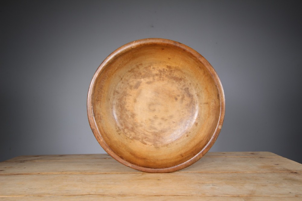 A large 19th-century turned sycamore wooden dairy bowl showing natural grain patina and turned rim detail. View V
