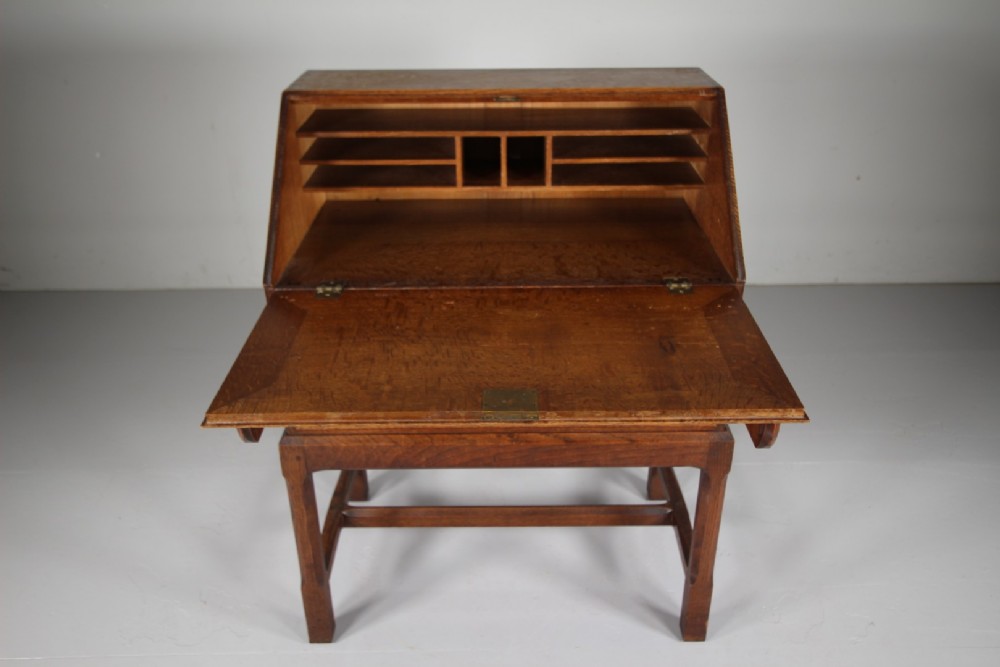 A 1930s oak writing bureau featuring a sloping fall-front lid over two drawers, supported by square legs with an H-stretcher. View III