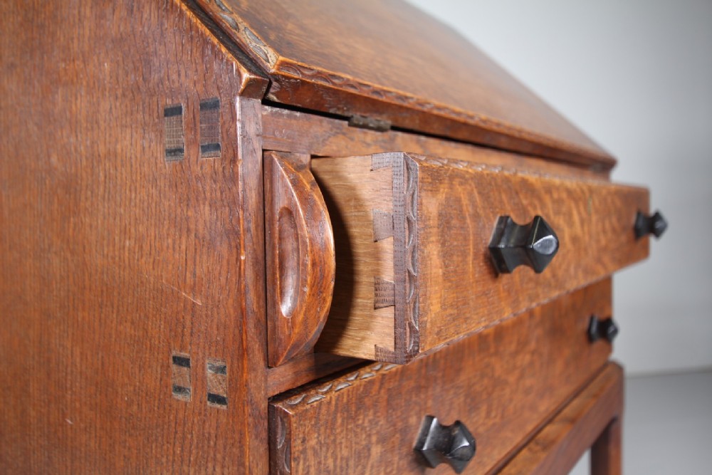A 1930s oak writing bureau featuring a sloping fall-front lid over two drawers, supported by square legs with an H-stretcher. View IV