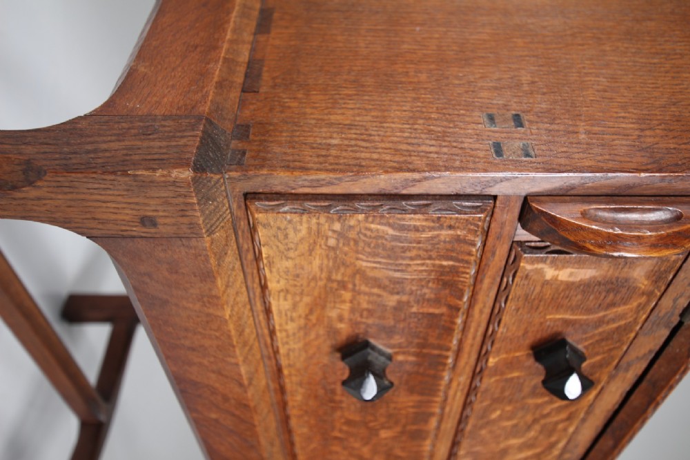 A 1930s oak writing bureau featuring a sloping fall-front lid over two drawers, supported by square legs with an H-stretcher. View V