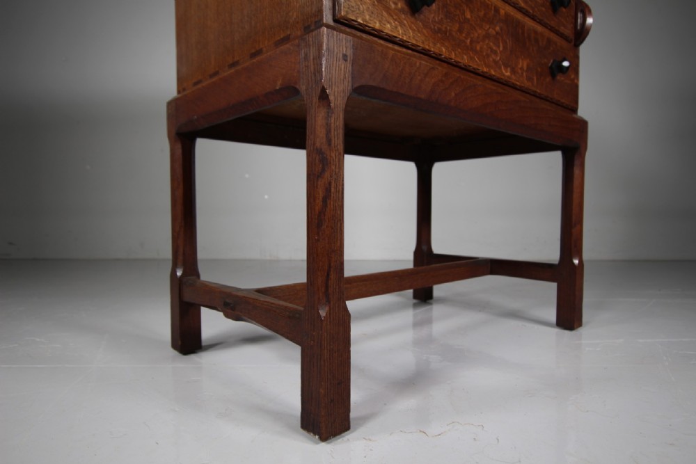 A 1930s oak writing bureau featuring a sloping fall-front lid over two drawers, supported by square legs with an H-stretcher. View VI