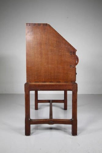 A 1930s oak writing bureau featuring a sloping fall-front lid over two drawers, supported by square legs with an H-stretcher. View VII