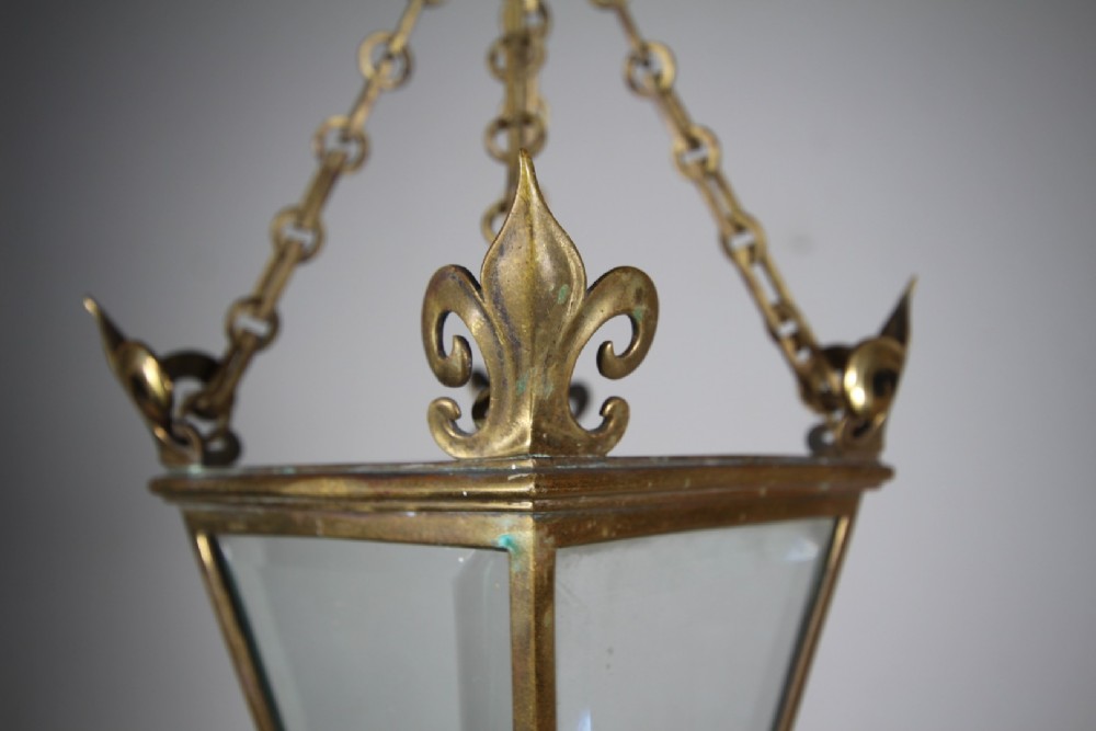 An early 19th-century inverted triangular brass hanging lantern with clear glass panels, corner finials, and suspension chains. View IV