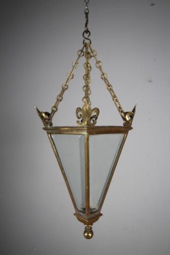 An early 19th-century inverted triangular brass hanging lantern with clear glass panels, corner finials, and suspension chains. View II