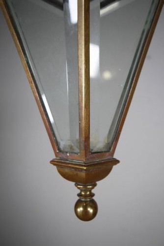 An early 19th-century inverted triangular brass hanging lantern with clear glass panels, corner finials, and suspension chains. View V