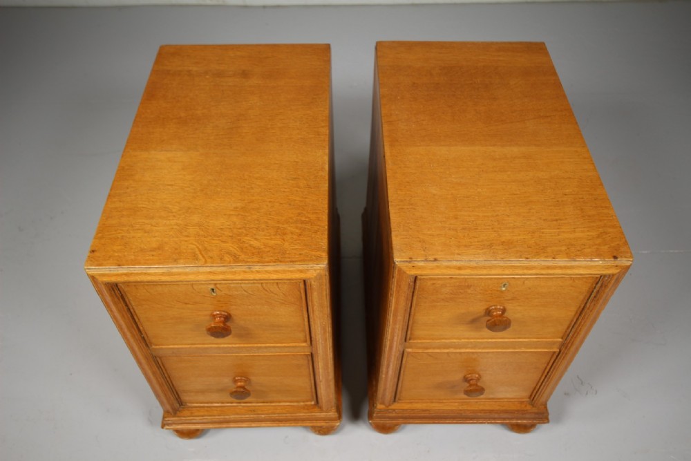A pair of antique golden oak bedside chests, each containing two drawers with turned wooden knob handles and resting on bun feet. View V