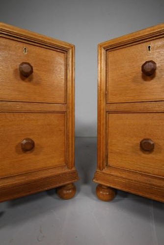 A pair of antique golden oak bedside chests, each containing two drawers with turned wooden knob handles and resting on bun feet. View IV