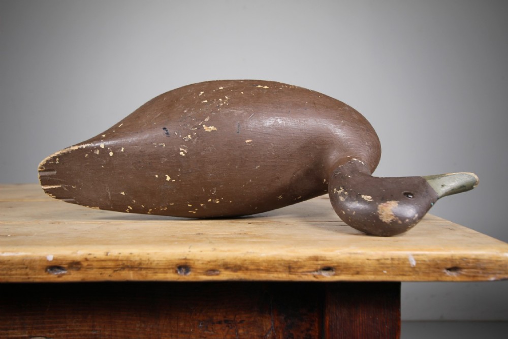 A 19th-century carved wooden decoy duck with a dark brown painted finish shown in profile. View V
