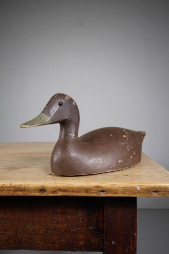A 19th-century carved wooden decoy duck with a dark brown painted finish shown in profile. View III