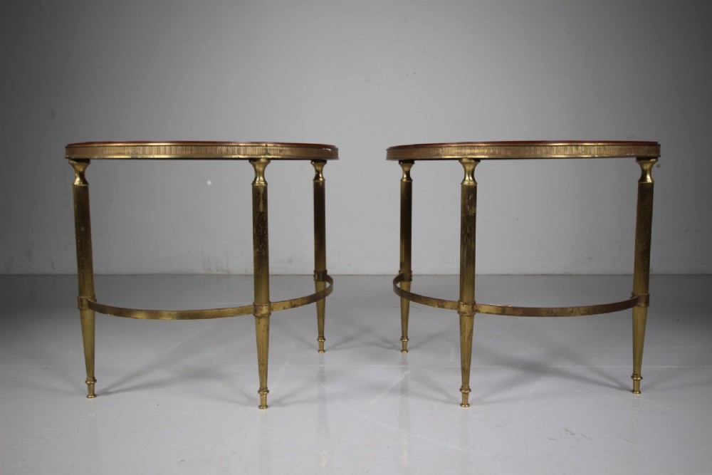 A pair of 1930s semi-circular brass side tables featuring fluted tapering legs, curved stretchers, and reeded edge aprons.