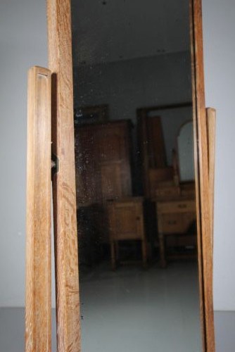 An antique Edwardian light oak cheval mirror featuring a rectangular tilting mirror frame set within two vertical posts resting on trestle feet. View II