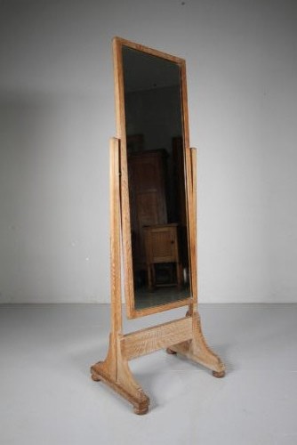 An antique Edwardian light oak cheval mirror featuring a rectangular tilting mirror frame set within two vertical posts resting on trestle feet. View III
