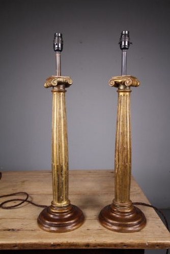 A pair of tall nineteenth-century gilt table lamps fashioned as fluted Ionic columns set on circular moulded bases.