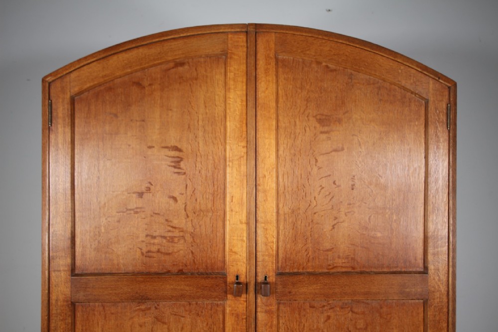 A 1930s oak double wardrobe featuring an arched top cornice, panelled twin doors, and a natural warm oak finish. View IV