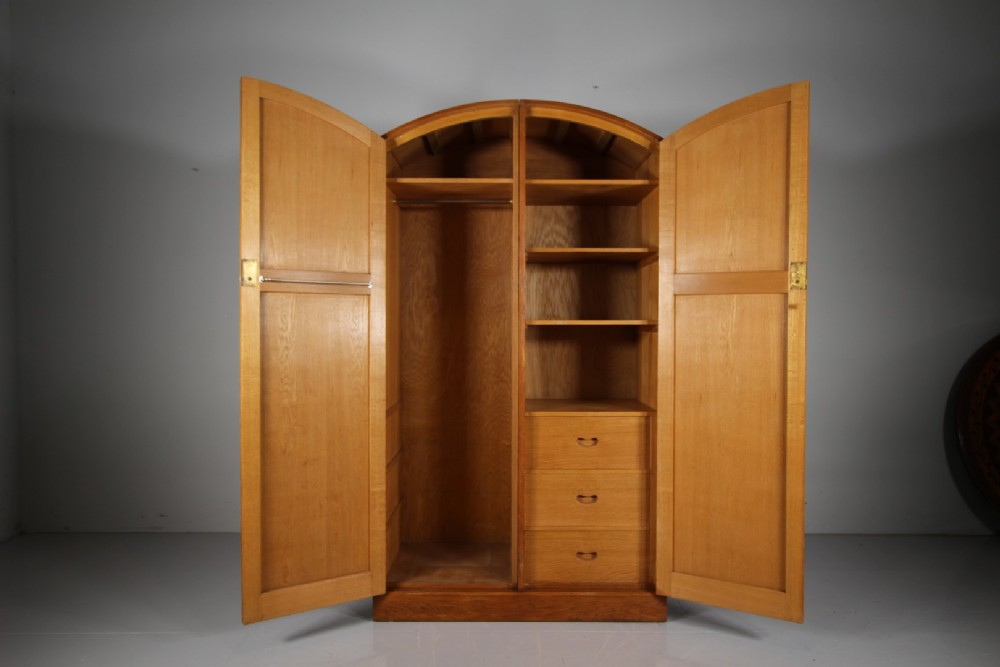 A 1930s oak double wardrobe featuring an arched top cornice, panelled twin doors, and a natural warm oak finish. View V