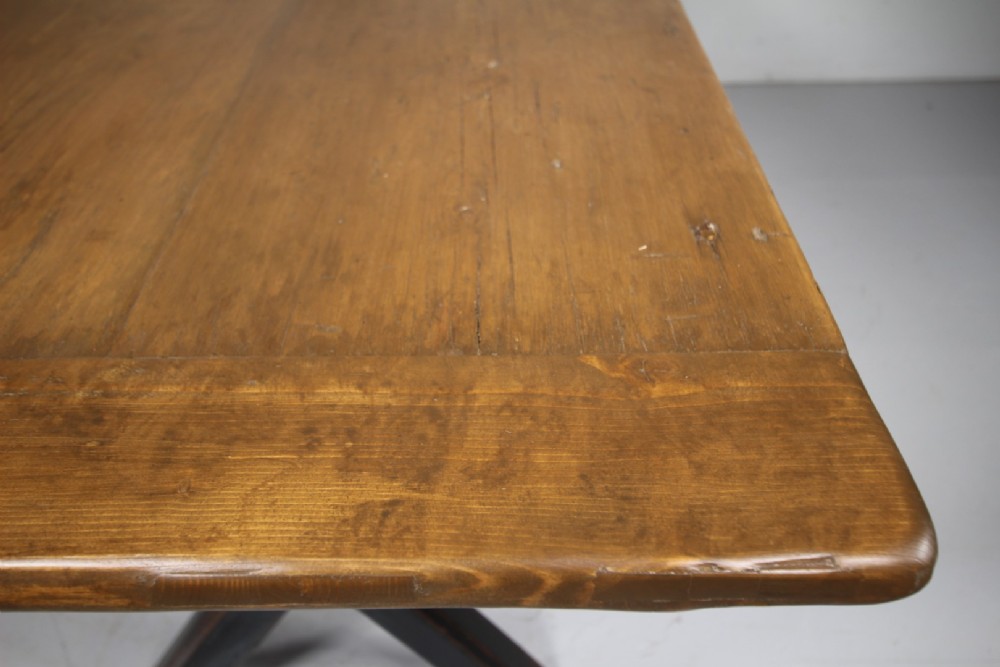 A 19th-century oak tavern dining table featuring a natural timber top, a black painted X-frame trestle base, and a central iron stretcher. View VI