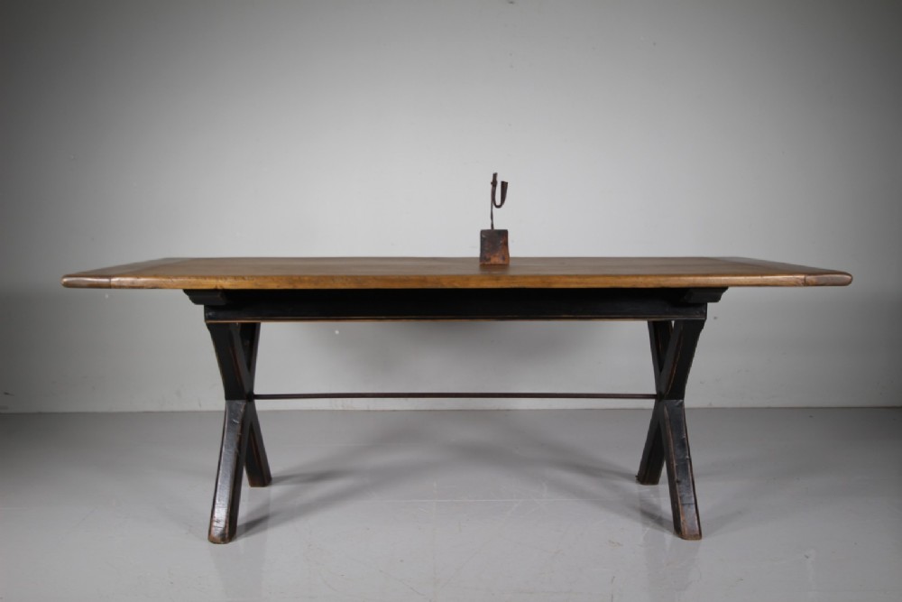 A 19th-century oak tavern dining table featuring a natural timber top, a black painted X-frame trestle base, and a central iron stretcher. View VII