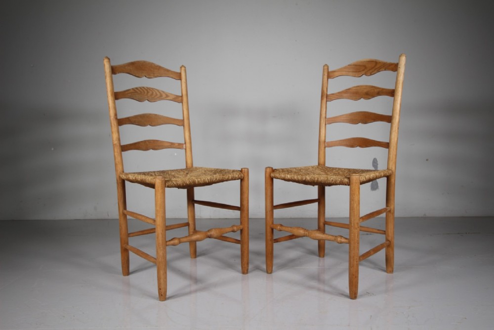 A pair of 1920s Arts and Crafts oak side chairs with ladderback frames and woven rush seats. View VI