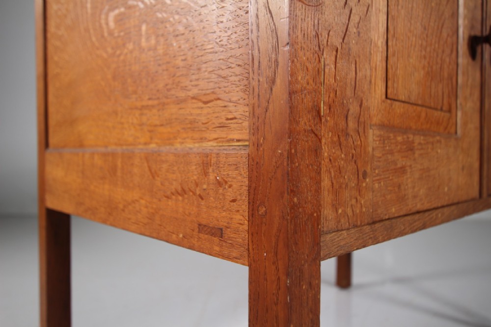 A solid oak two-door cupboard featuring recessed square door panels, carved wooden handles, and four square straight legs. View VIII