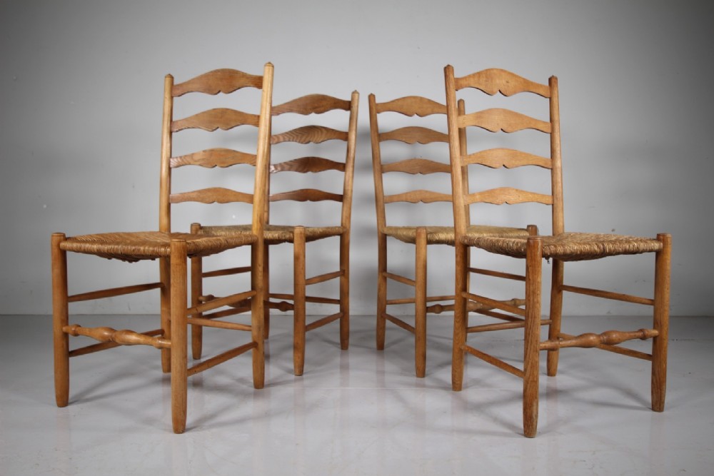 A set of four vintage Arts and Crafts ladderback dining chairs featuring natural woven rush seats and turned timber stretchers. View II