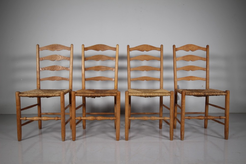 A set of four vintage Arts and Crafts ladderback dining chairs featuring natural woven rush seats and turned timber stretchers. View V