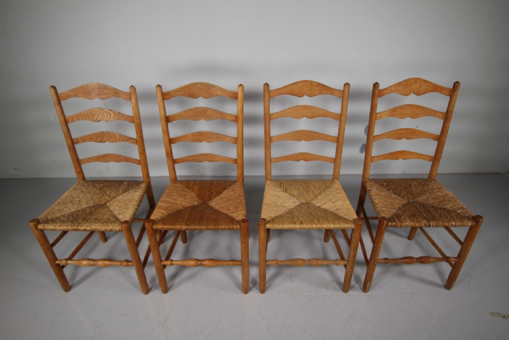 A set of four vintage Arts and Crafts ladderback dining chairs featuring natural woven rush seats and turned timber stretchers. View VII