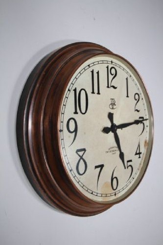 A circular antique Edwardian wall clock featuring a copper bezel, off-white dial with black Arabic numerals, and stylized spade hands. View IV