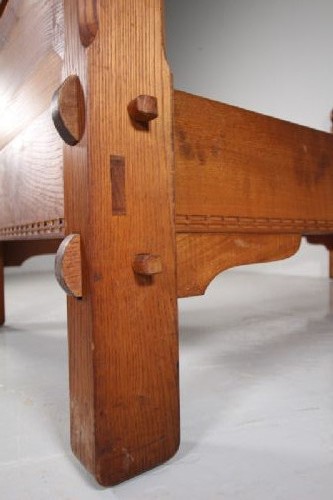 A 1930s solid oak single bed frame featuring carved geometric detailing, panelled headboard and footboard, and sturdy corner posts. View V