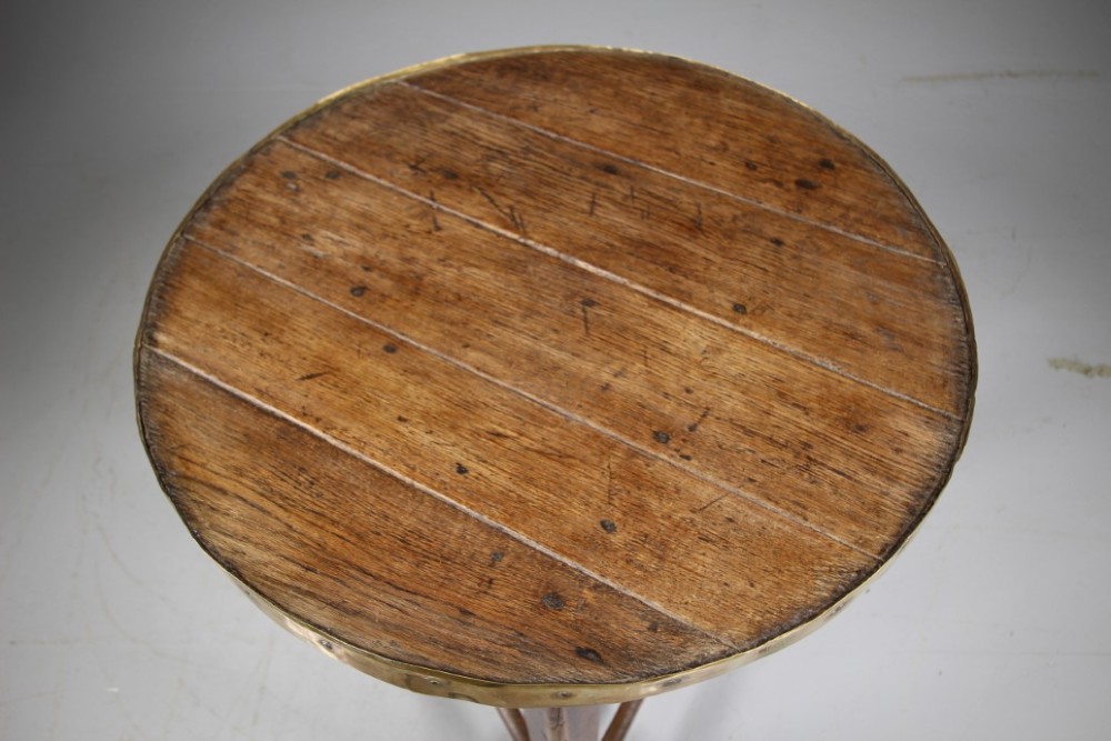 A nineteenth-century dark oak three-legged cricket table featuring a circular top bound with a studded brass rim and supported by a triangular stretcher. View III