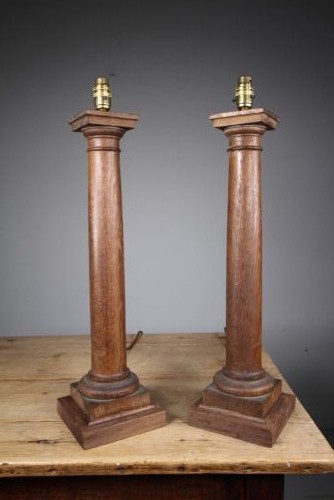 A pair of tall antique Edwardian oak table lamps carved in the form of classical architectural columns with square stepped bases and brass bulb sockets.
