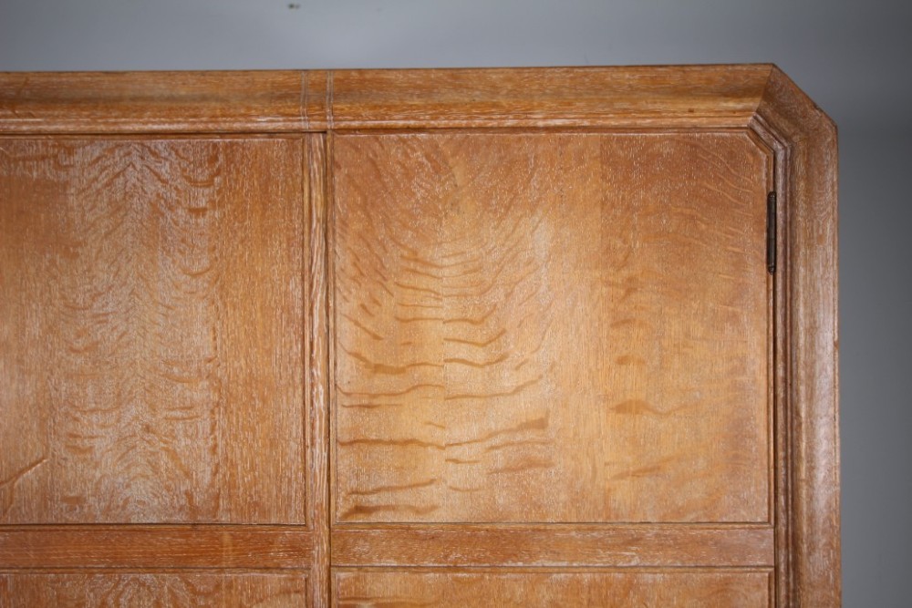 A 1920s Heals solid oak triple-door wardrobe with chamfered top corners, vertical wooden handles, and bun feet. View VIII