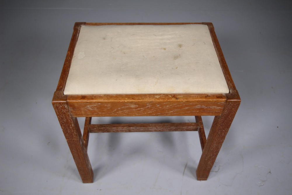 A 1920s oak stool featuring square straight legs connected by low stretchers and topped with a cushioned off-white seat. View III