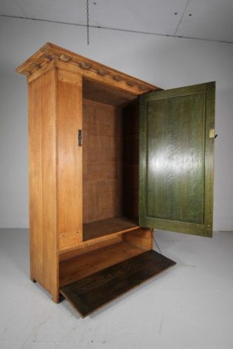 An Arts and Crafts solid oak cupboard featuring hand-forged wrought iron strap hinges, a single panelled door, and a lower drawer. View VII