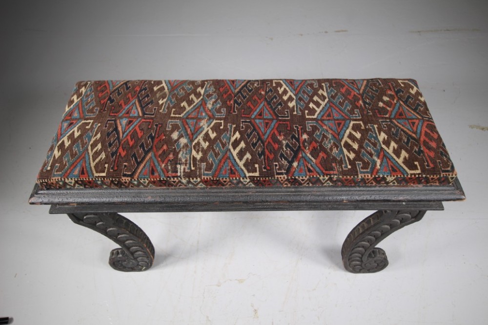 An early nineteenth-century black painted pine window seat featuring carved scroll legs decorated with repeating motifs and an upholstered geometric pad. View IV