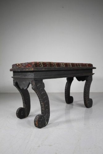 An early nineteenth-century black painted pine window seat featuring carved scroll legs decorated with repeating motifs and an upholstered geometric pad. View II