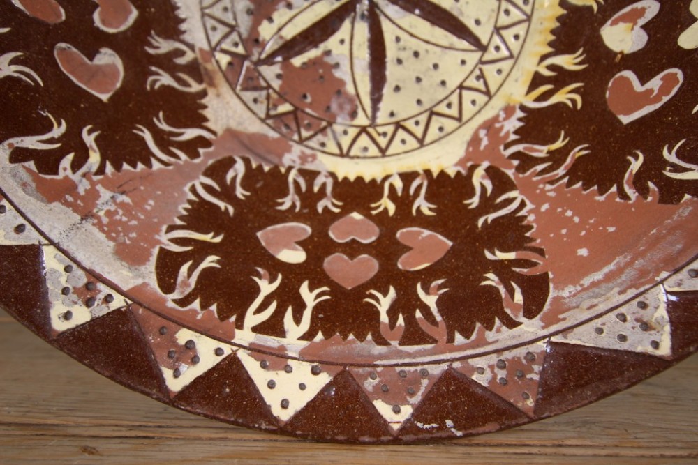 A large circular 19th-century slipware earthenware bowl decorated with cream geometric patterns, heart motifs, a central rosette, and inscribed text reading Margaret Wood Portlethen Dec 12th 1883. View III