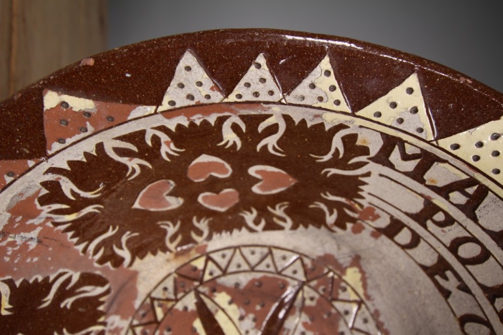 A large circular 19th-century slipware earthenware bowl decorated with cream geometric patterns, heart motifs, a central rosette, and inscribed text reading Margaret Wood Portlethen Dec 12th 1883. View VI
