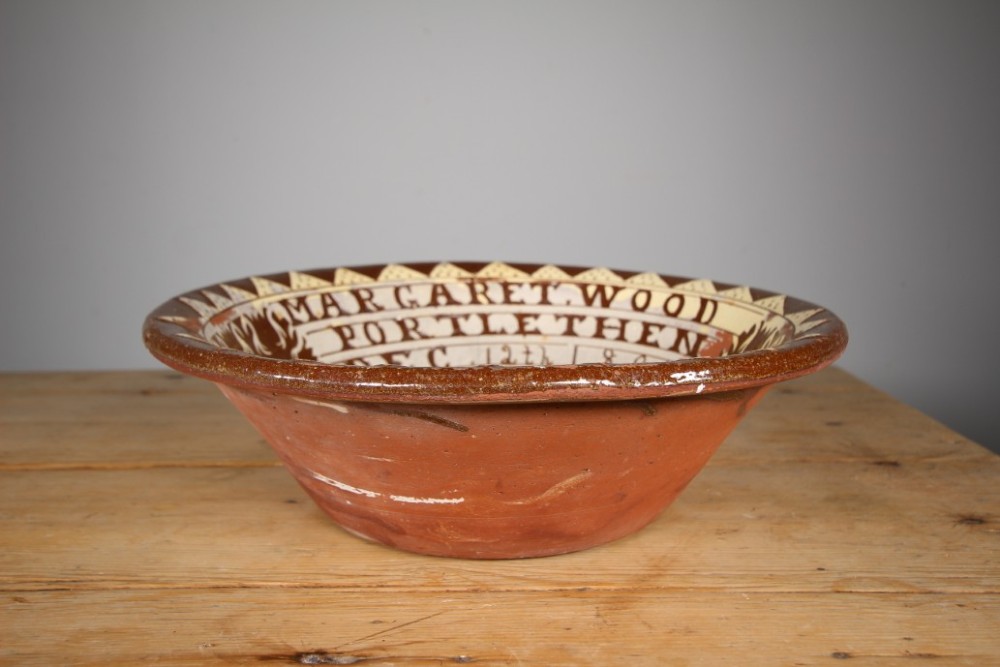 A large circular 19th-century slipware earthenware bowl decorated with cream geometric patterns, heart motifs, a central rosette, and inscribed text reading Margaret Wood Portlethen Dec 12th 1883. View VII