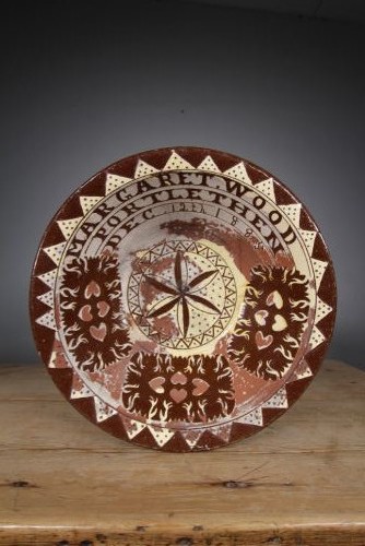 A large circular 19th-century slipware earthenware bowl decorated with cream geometric patterns, heart motifs, a central rosette, and inscribed text reading Margaret Wood Portlethen Dec 12th 1883. View II