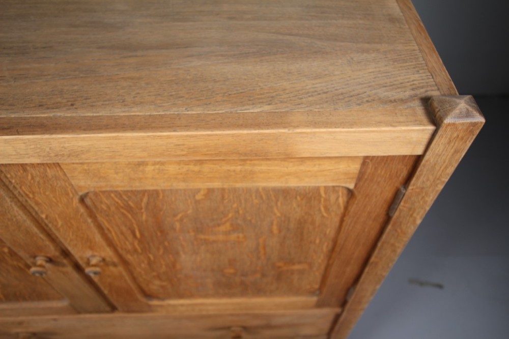 A 1920s Heals oak tallboy cupboard with two panelled upper doors above four wide graduated drawers fitted with circular wooden knobs. View III