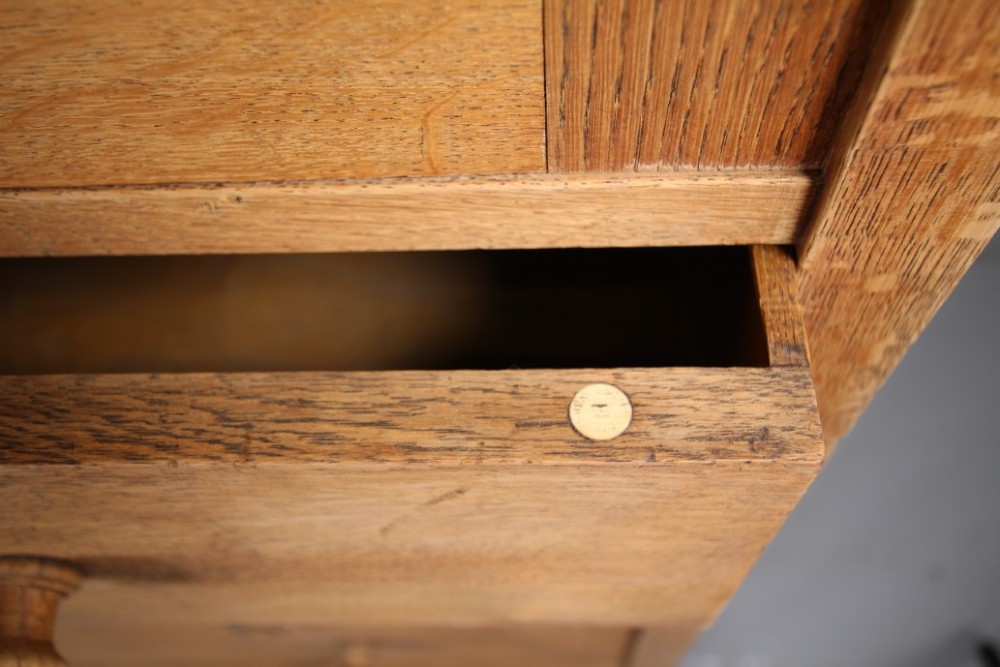 A 1920s Heals oak tallboy cupboard with two panelled upper doors above four wide graduated drawers fitted with circular wooden knobs. View VII