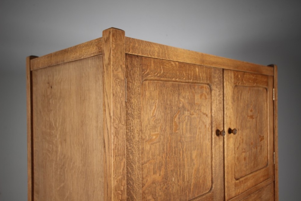 A 1920s Heals oak tallboy cupboard with two panelled upper doors above four wide graduated drawers fitted with circular wooden knobs. View IX