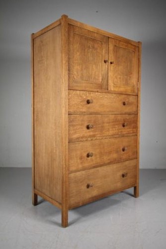 A 1920s Heals oak tallboy cupboard with two panelled upper doors above four wide graduated drawers fitted with circular wooden knobs. View VIII