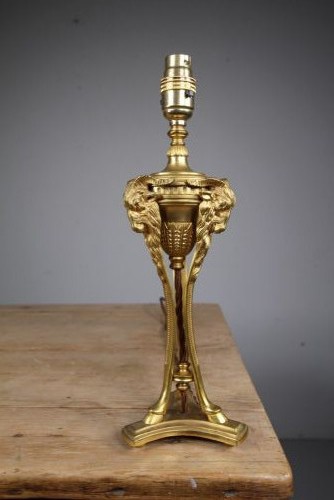 A 19th-century Neoclassical gilt bronze table lamp featuring a central urn, tri-form tripod legs terminating in rams heads, and a raised socket. View II