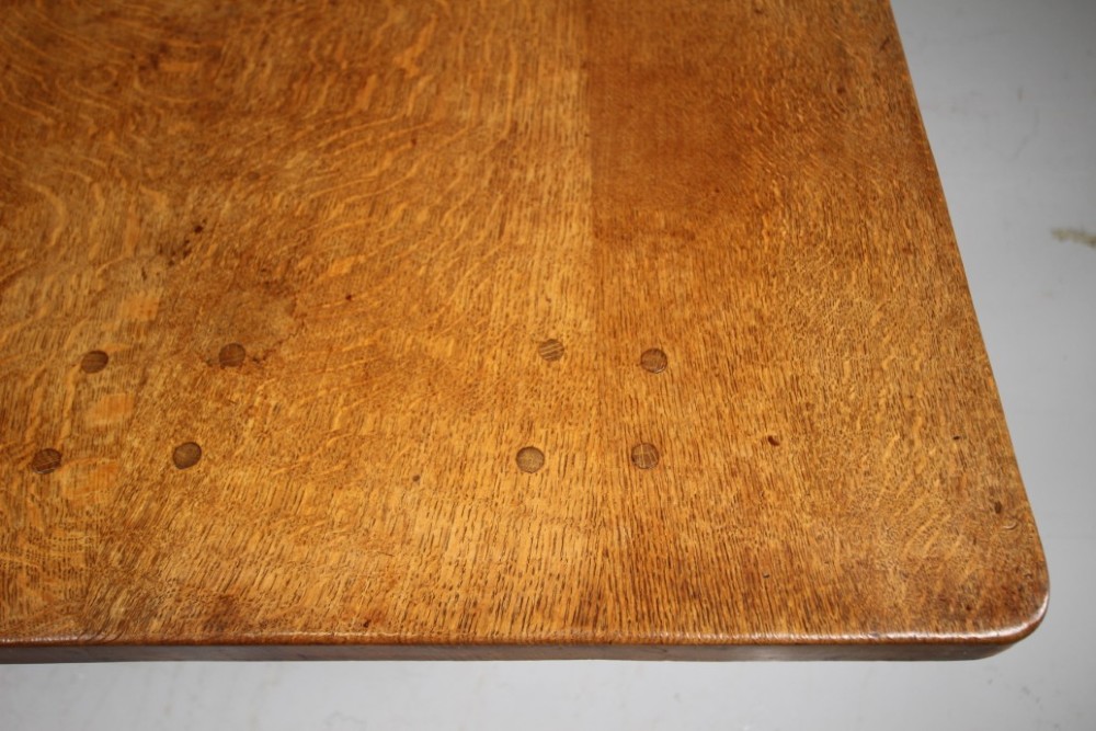 An English Arts and Crafts adzed oak refectory dining table featuring octagonal pedestal legs connected by a floor stretcher, displaying a carved mouse signature. View V