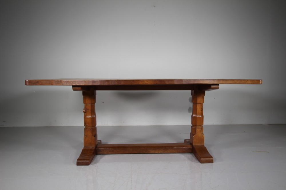 An English Arts and Crafts adzed oak refectory dining table featuring octagonal pedestal legs connected by a floor stretcher, displaying a carved mouse signature. View VII