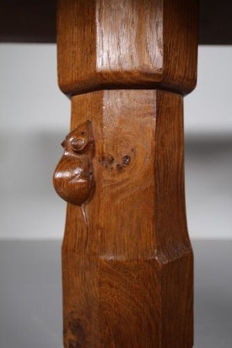 An English Arts and Crafts adzed oak refectory dining table featuring octagonal pedestal legs connected by a floor stretcher, displaying a carved mouse signature. View VIII