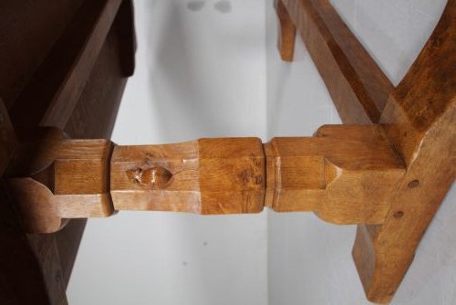 An English Arts and Crafts adzed oak refectory dining table featuring octagonal pedestal legs connected by a floor stretcher, displaying a carved mouse signature. View XI
