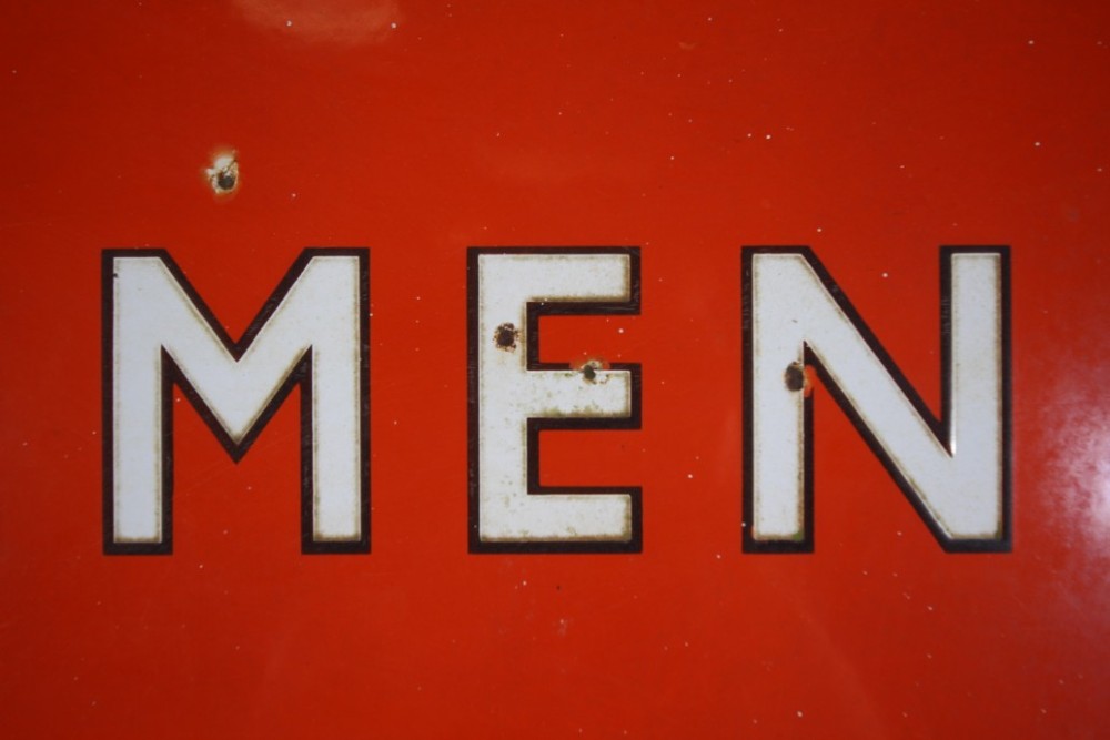 A rectangular red vitreous enamel railway sign featuring the word GENTLEMEN in bold white capital letters with black outlines. View III
